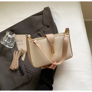 Detail of cream leather shoulder bag with brown trim and golden cylindrical metal lock