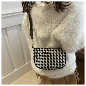 Detail of classic black and white houndstooth pattern on a crescent-shaped crossbody bag