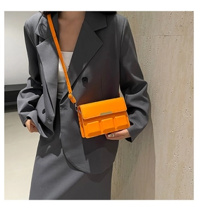Detail of orange square crossbody bag with 3D embossed cubes and gold metal trim