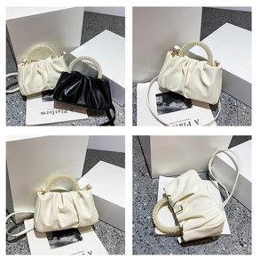 Detail view of cloud pouch bag featuring pleated texture and pearl circular top handles