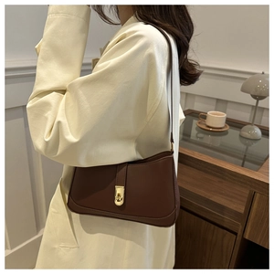 Detail of dark brown leather underarm bag with elegant gold twist lock closure