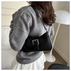 Detail of a black crescent baguette bag with large silver buckle on a stylish model