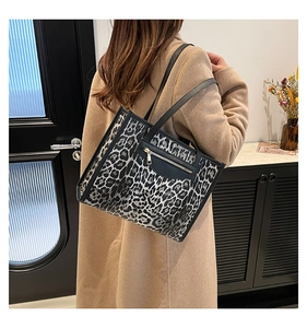 Shoulder shot of leopard print tote bag with black trim and golden zipper detail
