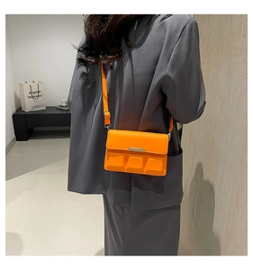 Detail view of a bright orange crossbody bag with unique 3D square embossed flap design