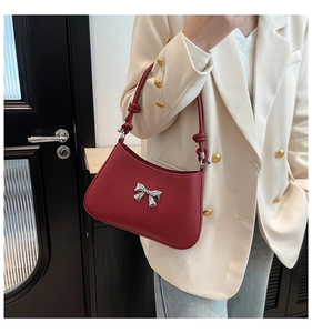 Détail du sac bandoulière rouge foncé avec nœud argenté et sangle décorative à nœuds