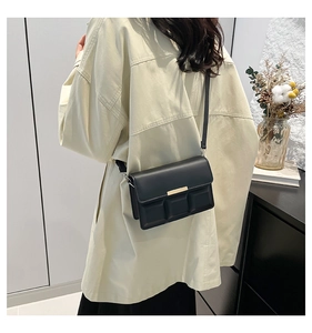 Detail of black crossbody bag featuring chocolate block texture and gold metal buckle