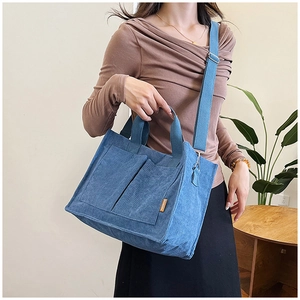 Blue corduroy tote bag detail showing dual front pockets and adjustable strap for crossbody use