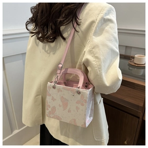 Detail of pink butterfly pattern and silver glitter on a white leather tote bag