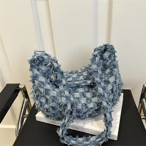 Denim hobo bag with blue plaid fringe and wide shoulder strap in a stylish hobo design