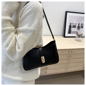 Detail of vintage black leather underarm bag with gold twist lock on shoulder
