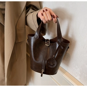 Dettaglio di una borsa a secchiello marrone vintage con charm sorriso e pelle in PU