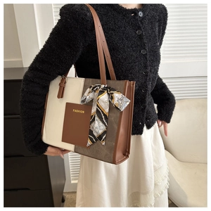 Detail of color-block tote bag with beige canvas, brown leather pocket, and fashion scarf