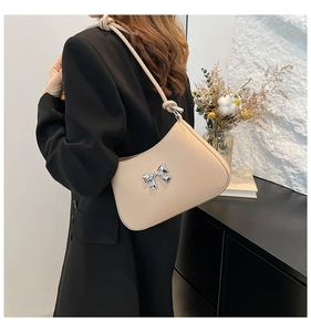 Détail d'un sac hobo beige avec nœud métallique argenté et bandoulière en cuir noué