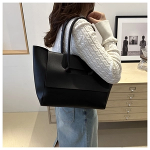 Detail view of large black tote bag with matte finish texture and sleek shoulder straps
