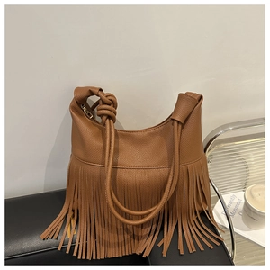 Detalle del bolso hobo de cuero granulado marrón caramelo con flecos largos y asa anudada