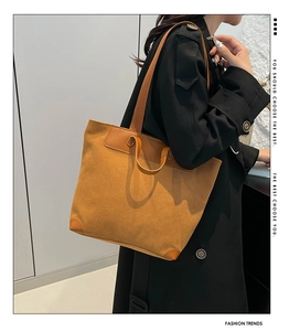 Model showing large mustard corduroy tote bag with brown leather accents and dual straps
