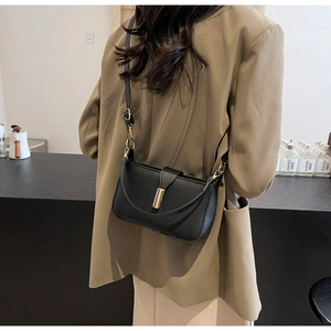 Detail of a sleek black leather crossbody bag with a gold rectangular metal lock mechanism