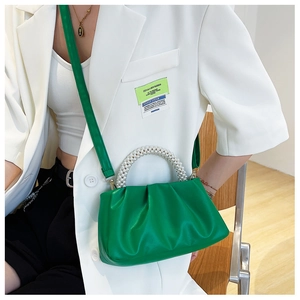 Detail of green ruched cloud bag featuring decorative pearl handle and soft leather texture