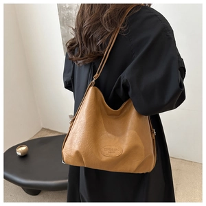 Close-up of caramel hobo bag with pebble leather texture and embossed logo detail