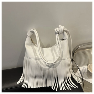 Detalle de cuero blanco con textura de grano y flecos largos en bolso de bandolera