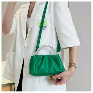 Detail of green cloud bag with pearl handle and leather texture on a white suit