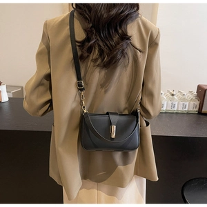 Minimalistische schwarze Leder Umhängetasche mit goldener Schließe lässig über der Schulter