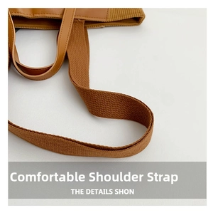 Detail of wide woven fabric strap and matching brown leather handle on a large tote bag