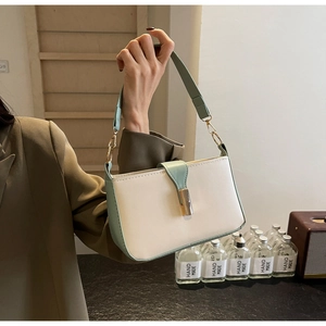 Detail der farblich abgesetzten Tasche in Creme und Minze mit Goldschnalle auf Blazer