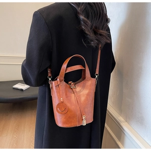 Détail du sac seau vintage en cuir caramel avec ornement cadenas et patch sourire