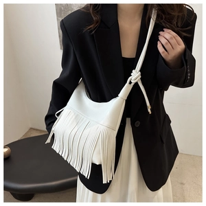 Close-up of white lychee texture crossbody bag with long tassels and knotted strap detail