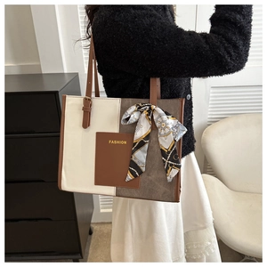 Detail of color-block tote bag featuring beige canvas, brown leather pocket and silk scarf