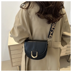 Detail of black leather saddle bag with gold horseshoe buckle and patterned strap