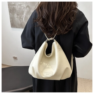 Detail view of a cream PU leather tote bag with a gold logo and fine chain strap