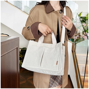 Detail of cream corduroy tote bag featuring front pockets and brown fashion leather tag