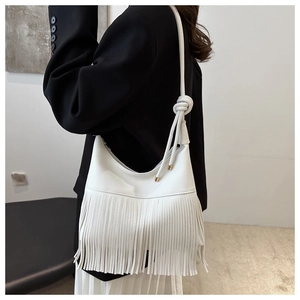 Detalle del bolso hobo blanco con flecos y nudo decorativo en la correa al hombro