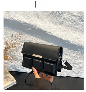 Detail of black rectangular crossbody bag with matte finish and gold magnetic clasp