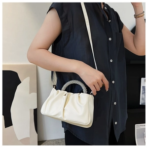 Detail of white cloud bag featuring pearl handle and elegant pleated texture design