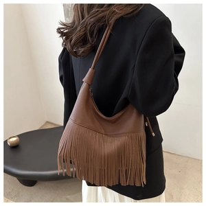 Close-up of a vintage dark brown leather tote bag featuring long bohemian fringe details