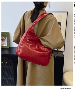 Red glossy large capacity shoulder bag shown on model with chic trench coat outfit