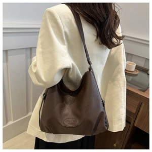 Close-up of dark brown hobo bag with vintage texture and embossed brand logo detail