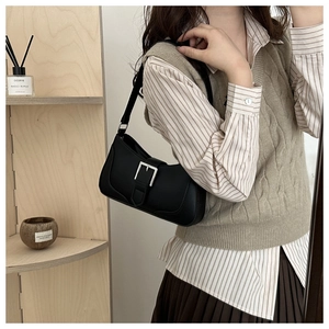Detail of matte black crescent bag with silver buckle worn on shoulder