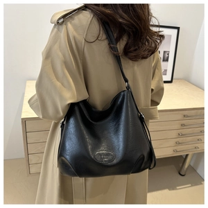 Detailed view of large black leather hobo bag with embossed logo on a female model