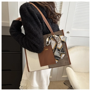 Detail of contrast stitching on faux leather tote bag with elegant scarf decoration