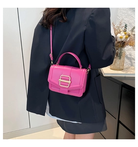 Sac bandoulière en cuir rose fuchsia avec boucle dorée porté pour l'échelle réelle