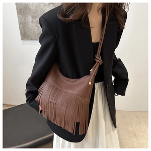 Close-up of brown pebbled leather hobo bag featuring long fringe and knotted shoulder strap