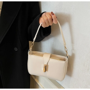 Detail der minimalistischen cremefarbenen Baguette-Tasche mit goldener Schnalle und Naht
