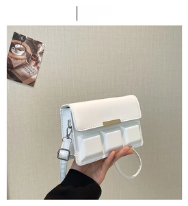 Close-up of white crossbody bag with chocolate grid texture and gold buckle