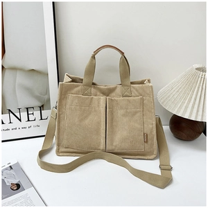 Detail of beige corduroy tote bag showing front pockets and adjustable shoulder strap