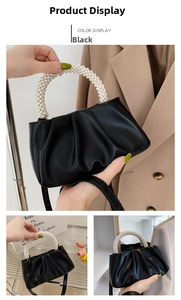 Detail of black pleated cloud bag featuring three-row faux pearl handle and cross-body strap