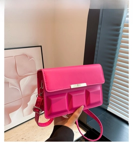 Detail of rose red crossbody bag with 3D chocolate square texture and gold metal bar